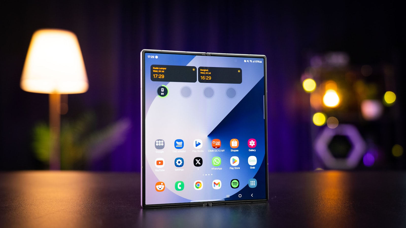 Android-смартфон флагманского класса стоит раскрытым на столе в вечерней обстановке с боке