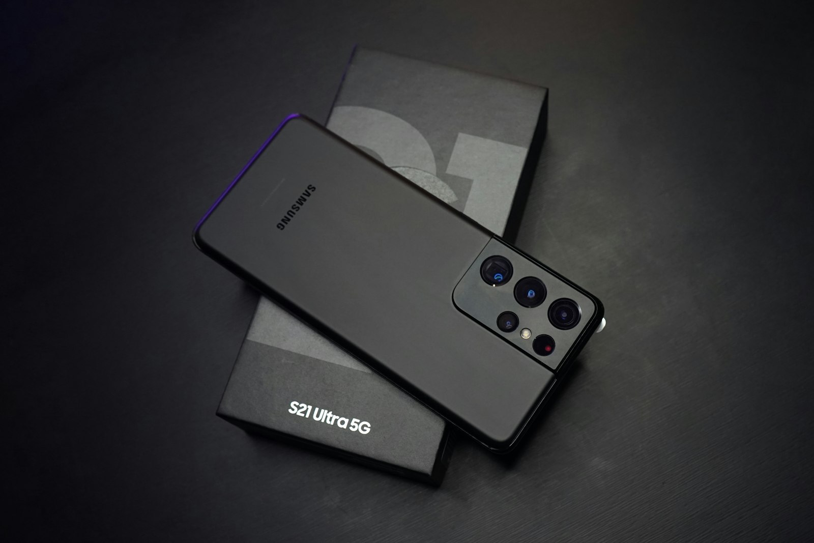 Чёрный смартфон Samsung задней панелью вверх лежит на фирменной коробке