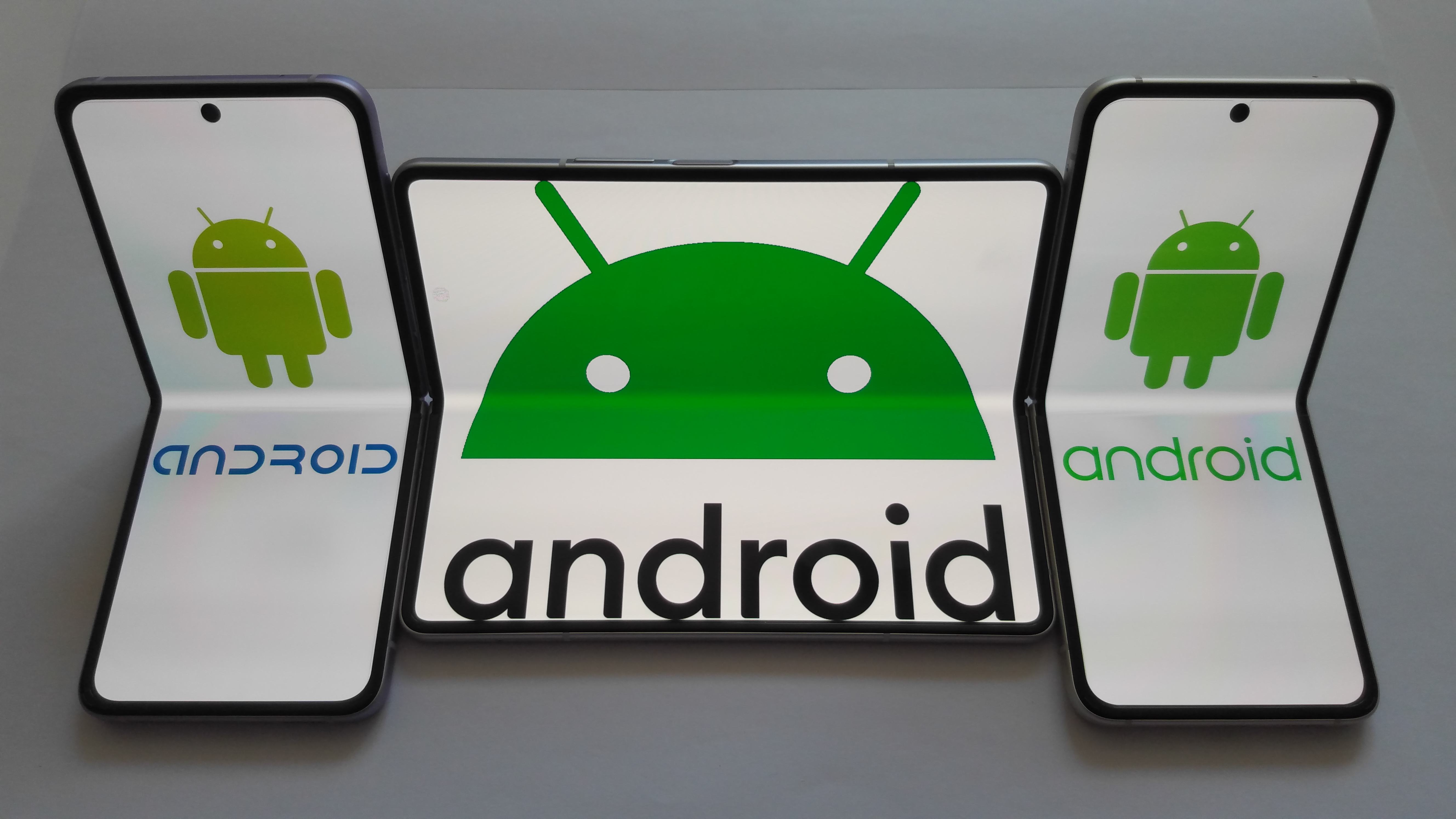 Складные смартфоны с логотипом Android на экранах на светло-сером фоне