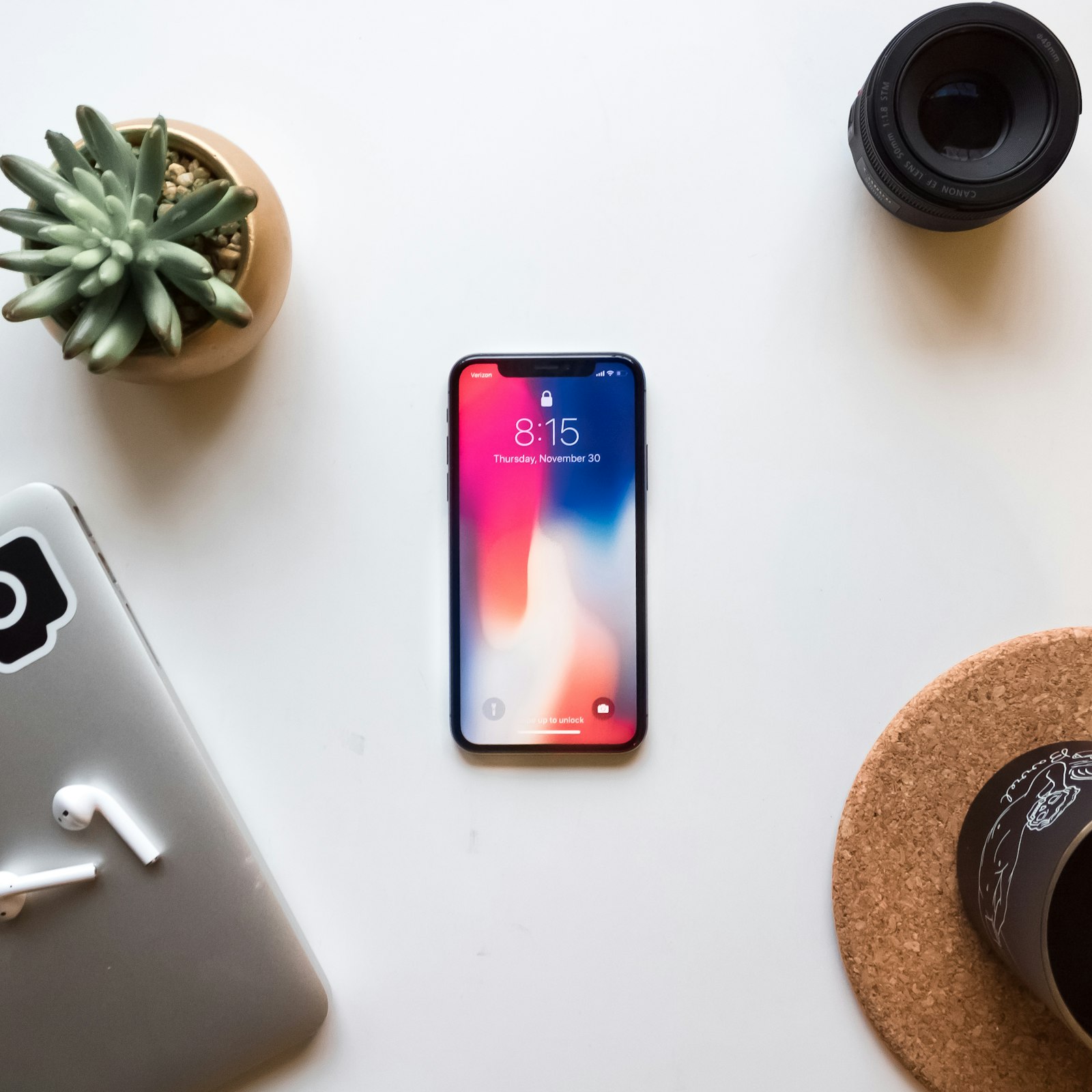 Смартфон с ярким iOS-экраном на рабочем столе рядом с наушниками и объективом камеры — обновление iOS 27 Golden Gate 2026